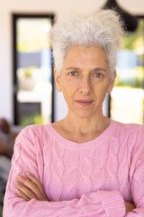 Close-up portrait of confident caucasian senior woman with arms crossed standing in nursing home