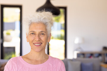 Close-up portrait of smiling caucasian senior woman against white wall in nursing home, copy space