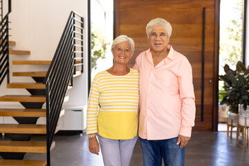 Portrait of smiling biracial senior friends standing against wooden door in nursing home