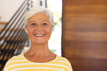 Close-up portrait of smiling biracial senior woman with short hair against door in nursing home - Powered by Adobe