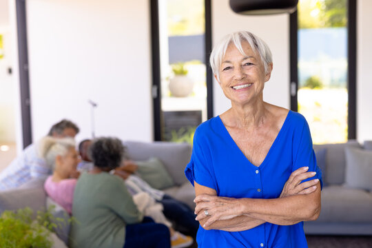 Portrait of happy asian senior woman with arms crossed standing against multiracial friends