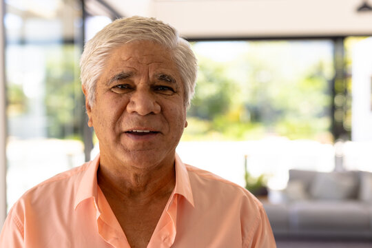Close-up portrait of smiling biracial senior man against windows in nursing home