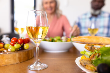 Close-up of wineglass with meal on dining table with seniors in background at nursing home