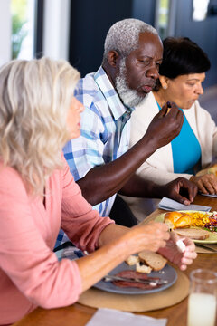 African American Senior Man Eating Lunch With Multiracial Female Friends At Dining Table