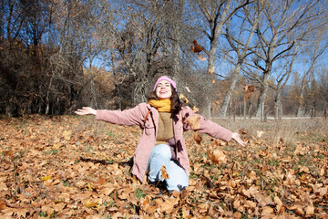 Mujer alegre lanzando hojas de otoño en el aire