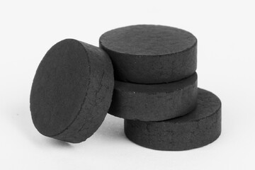 Absorbent, activated charcoal tablets on a white background.
