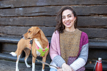 Mujer turista sentada con su perro mascota en un banco de una cabaña en el bosque