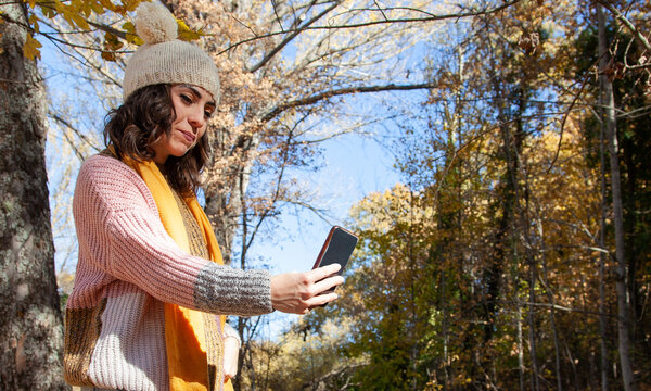 Mujer haci&eacute;ndose selfies en el campo. Chica usando el tel&eacute;fono m&oacute;vil en una excursi&oacute;n.