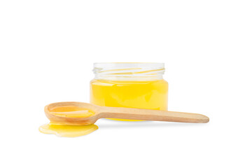 Jar with honey and next to a wooden spoon with honey spilled