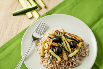 pearl barley salad with zucchini on white dish whit fork