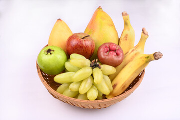 All fruits like Banana, Ripe Mango, Guava, Java Apple, Apple, Grapes in basket isolated on white background.