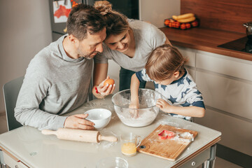 Young couple, man and woman Teaches son 4 - 5 years to Bake cookies, knead dough, work with flour in kitchen at home, happy hours of young family