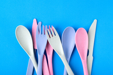 Cutlery set made of wheat straw of pastel colors on blue background. Reusable utensils. School...