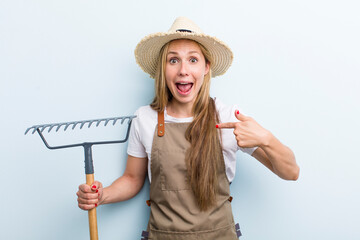 young adult blonde woman. farmer with a rake