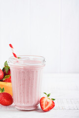 Strawberry smoothie. Vegan smoothie or milkshake from strawberry, banana and mint on white wooden table background. Clean eating, alkaline diet. Top view. Mock up.