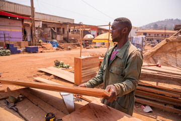 An african carpenter during work takes a board of wood to be cut