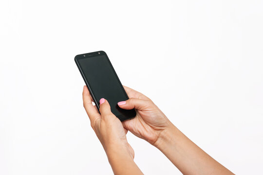 Mobile phone with black screen in female hands isolated on a white background. Blank with an empty copy space for the text. Template for the design. Mockup of a smartphone. A young woman using phone