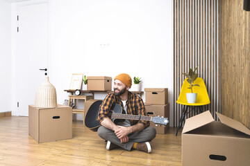 Hipster man with moving boxes in new modern apartment. Mature man unpacking things from boxes while moving in new apartment. 