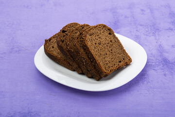 sliced rye bread in pieces in a white plate on a wooden background