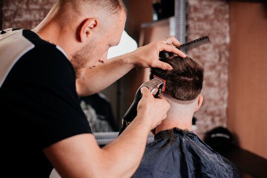 Professional barber working with client in hairdressing salon