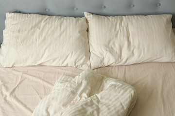 Rumpled unmade bed, sheets and pillows