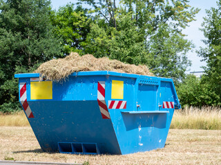 Container with lawn clippings on a meadow