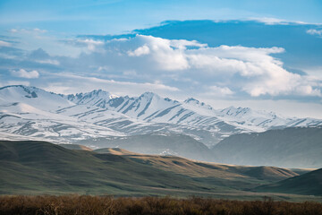 Obraz premium Sunset in the mountains, clouds and snowy peaks, slopes of the Tien Shan mountains, Suusamyr, Kyrgyzstan
