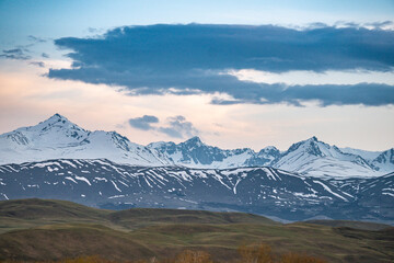 Sunset in the mountains, clouds and snowy peaks, slopes of the Tien Shan mountains, Suusamyr, Kyrgyzstan