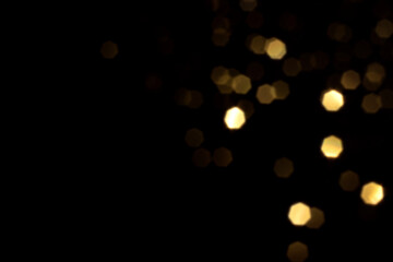 Golden blurred bokeh lights on black background. Glitter sparkle stars for celebrate. Overlay for your design