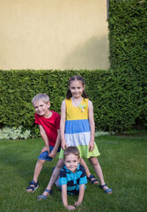 Portrait of three small children in a park on green grass, looking at the camera. During the summer, siblings spend time outdoors. Friendship, childhood, joy, holidays. copy space