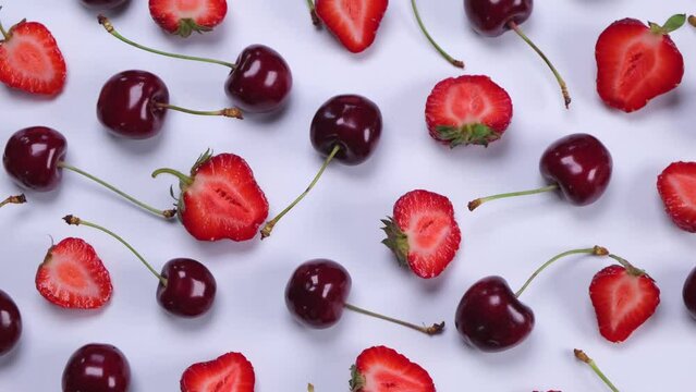 Rotating background of ripe strawberries and cherries on a white background.Trendy,fruity,summer loop background