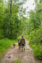 Fototapeta premium Two men with dog in forest walk
