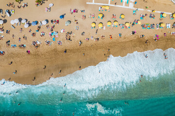 Fototapeta na wymiar aerial shooting from a drone on a sandy beach with people sunbathing and relaxing. Flat view of the shore and turquoise waves of the surf and people bathing