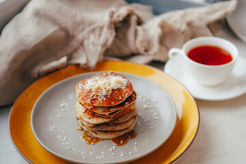 Banana Pancakes with maple syrup and coconut flakes for breakfast on table