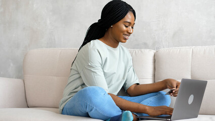 Woman makes purchases, pays for educational courses online while sitting on the couch with a credit card. Online shopping. Hands close-up © ALFImedia