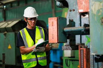 Metal machine in heavy Industry Manufacturing. Asian male factory worker wearing safety hard hat...