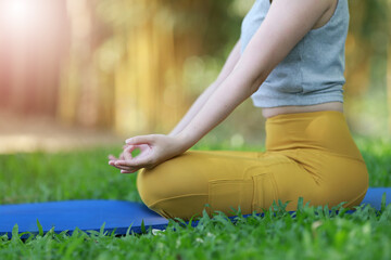 Close up of woman practice yoga meditation exercise in park, beautiful female sitting on mat for relaxed yoga posture in the morning , exercise at park, mental health care,healthy and sport