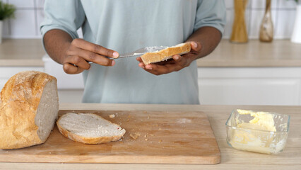 Smear organic butter on bread. Soft butter spreading on slice of sourdough bread. Carbohydrates, fat concept