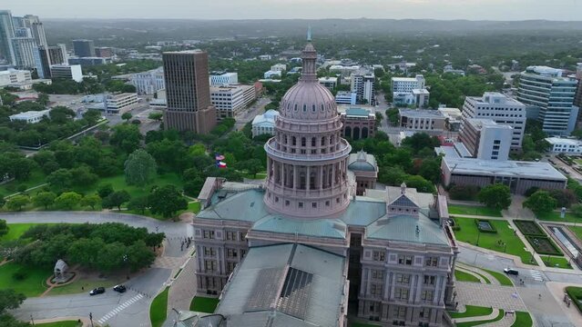 Aerial orbit of Texas State Capitol building and dome in Austin Texas. TX skyline in distance. Home of Texas Governor Abbott.