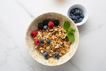 Granola with berries in a bowl for breakfast on light table top view healthy food