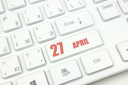 April 27th. Day 27 of month, Calendar date. Cropped view of Modern White Computer Keyboard with calendar date. Concept workspace, freelance, deadline.  Spring month, day of the year concept.