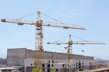 Fototapeta na wymiar Industrial background of construction cranes at the construction site build residential buildings of block flat or apartment from modern concrete panels