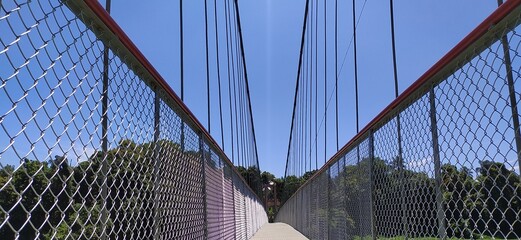 Outdoor hanging suspension bridge structure made with iron metal cable rope and tower for crossing...