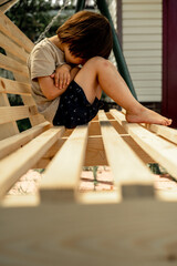 a three-year-old boy is sitting in the backyard of a village house, he is crying and offended, the...