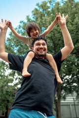 a happy, laughing baby sits on dad's shoulders, they dance and have fun. A father spends time with his son. The concept of a happy family
