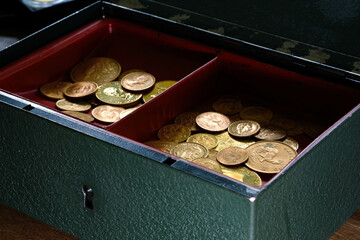 Ein Haufen Goldmünzen liegt in einer geöffneten Geldkassette
