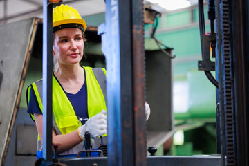 Caucasian female warehouse worker driving forklift truck at factory warehouse.