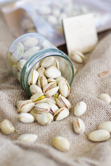 Fototapeta na wymiar Pistachios close-up, crumble out of the jar. The background is burlap. Photo of nuts, proper nutrition