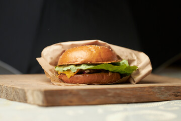 Burger on a turf board. Burger with brioche, beef, slat romaine, tomato, cucumber, cheddar cheese and onion.  