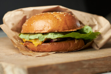 Burger on a turf board. Burger with brioche, beef, slat romaine, tomato, cucumber, cheddar cheese and onion.  